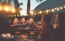 Happy Family Dining And Tasting Red Wine Glasses In Barbecue Dinner Party - People With Different Ages And Ethnicity Having Fun Together - Youth And Elderly Parents And Food Weekend Activities Concept