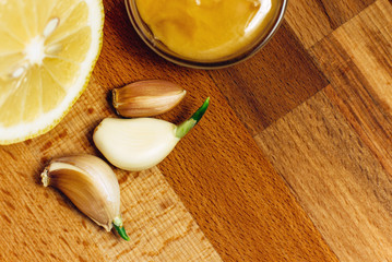 Means of traditional medicine. Garlic, honey and lemon on a wooden board