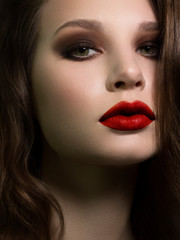 Wall Mural - Beautiful brunet model woman face with green eyes and perfect make-up. Portrait of beauty young brunet girl with red lips and smoky eyes, thick eyesbrow . Female face with clear skin close-up.