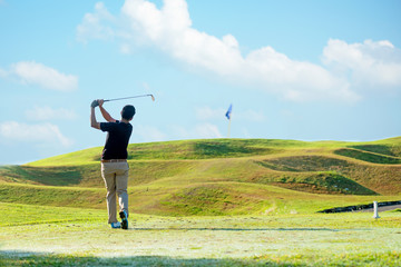 Professional golfer asian man approach on the tee off for swing and hitting golf ball and looking fairway in course. Hobby in holiday and vacations sunny morning  club golf.  Lifestyle sport Concept.