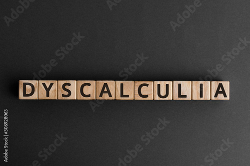 Photo Dyscalculia - word from wooden blocks with letters, learning disability in math