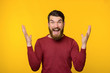 © Vulp - Bearded young man being surprised near yellow wall.