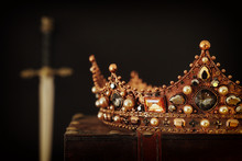 Low Key Image Of Beautiful Queen/king Crown Over Antique Box Next To Sword. Fantasy Medieval Period. Selective Focus