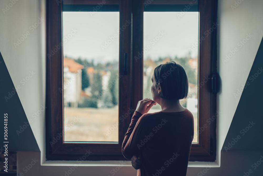 Sad woman looking out of the window - obrazy, fototapety, plakaty 