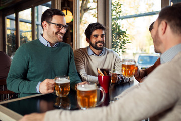 Wall Mural - Group of happy friends drinking beer in pub