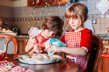 Cute, little girls in chef apron making ginger cookies, coloring them.