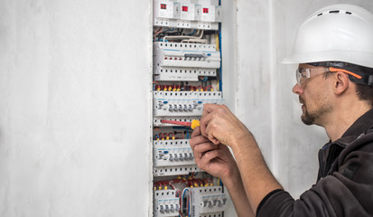 Man, an electrical technician working in a switchboard with fuses. Installation and connection of electrical equipment.