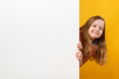 © Olga - Cute happy cheerful little girl holding a blank white space banner on a yellow background