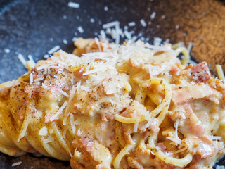 Closeup macro detail of authentic spaghetti carbonara made with eggs, guanciale, and Pecorino Romano cheese, at an Italian restaurant. Bangkok, Thailand. Travel and cuisine.