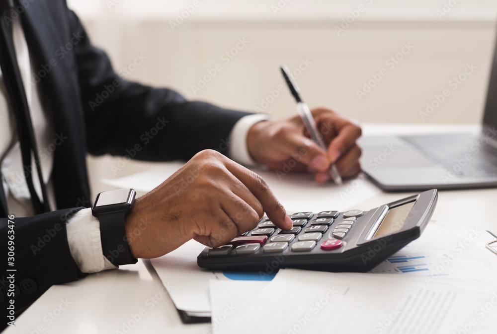 Close up of man checking on incomes, using calculator - obrazy, fototapety, plakaty 