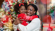 © Prostock-studio - Portrait of happy black mother and daughter posing near Christmas tree