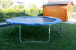 Home street trampoline on an aluminum frame, black with a blue border. Children's trampoline for jumping is installed on the street on the green.
