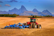 Tractor Farming Ground Harvesting Crops in Fall Autumn Teton Mountains Rugged