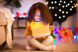 © Prostock-studio - Surprised little african girl opening glowing Christmas gift
