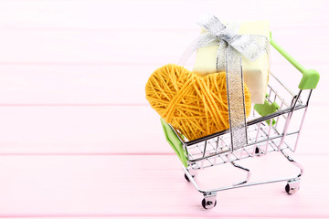 Wall Mural - Shopping cart with rope heart and gift box on pink wooden table