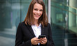© Minerva Studio - Smiling businesswoman using a smartphone outdoor