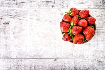 Wall Mural - Ripe strawberries forest fruits in wooden bowl on white table. Fresh strawberry top view.