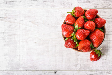 Wall Mural - Ripe strawberries forest fruits in wooden bowl on white table. Fresh strawberry top view.