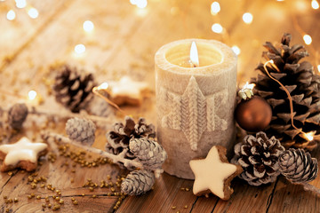 Christmas background - Advent candle with natural Xmas decoration, branches and pine cones on rustic wood