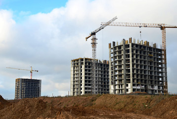 Wall Mural - Tower cranes constructing a new residential building at a construction site against blue sky. Renovation program, development, concept of the buildings industry.