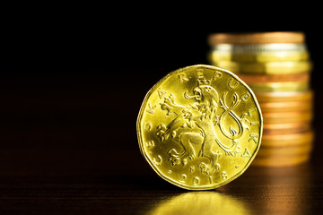 Businessman holds a yellow coin with his finger. Czech korunas on the table. Yellow coins on the table. Twenty Czech korunas.