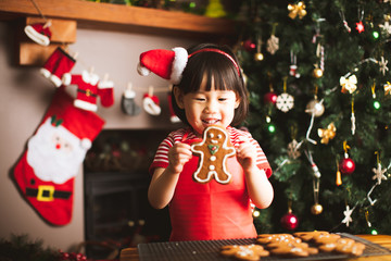 toddler girl making gingerbread man in front of Christmas tree