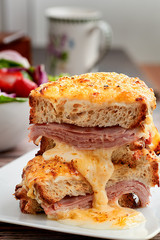 Wall Mural - Sandwich with Parmesan and Gruyere cheese, ham, béchamel sauce and artisan bread accompanied by a salad on a wooden background.  The Croque Monsieur.