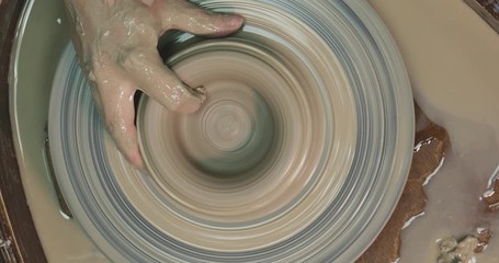 Wall Mural - Woman hands on pottery wheel, potter at work. Craftsman artist shapes pot