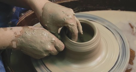 Wall Mural - Woman hands on pottery wheel, potter at work. Craftsman artist shapes pot