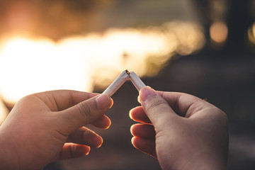 Men hand caught a burning cigarette causing smoke, concept stop smoking.