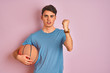 © Krakenimages.com - Teenager boy holding professional basket ball over isolated pink background annoyed and frustrated shouting with anger, crazy and yelling with raised hand, anger concept