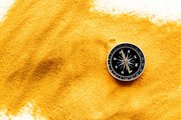 Wall Mural - Travel concept. Compass on yellow sand background top view copy space