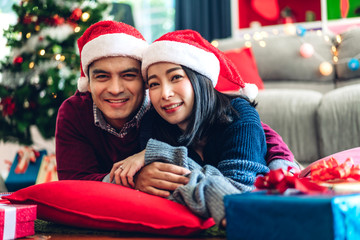 Romantic sweet couple in santa hats having fun and smiling while celebrating new year eve and enjoying spending time together in christmas time at home