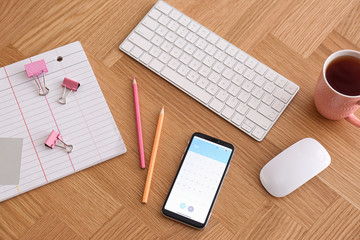 Wall Mural - Smartphone with calendar app on wooden table, above view