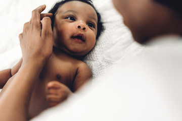 african american mother playing with adorable little african american baby in a white bedroom.love o