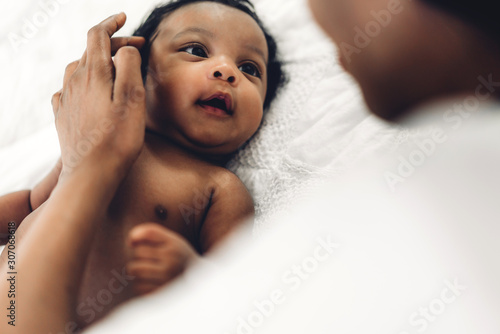 Fotomural African american mother playing with adorable little african american baby in a white bedroom