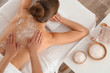 © New Africa - Young woman having body scrubbing procedure with sea salt in spa salon, top view