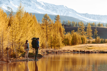 couple of hikers with backpacks near mountain lake