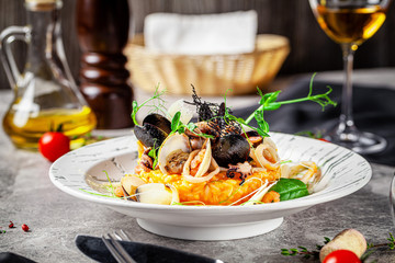 Italian food concept. Risotto with seafood, mussels, octopuses, squid. Serving dishes in a white plate. Modern serving in a restaurant. Background image. Copy space.