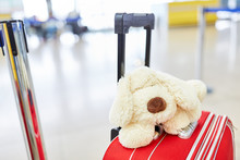 A Cuddly Toy Lies On A Rolling Suitcase