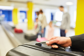 Wall Mural - Hand holds a suitcase while picking up from the luggage belt