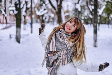 smiling beautiful woman in a scarf having fun on the nature in winter