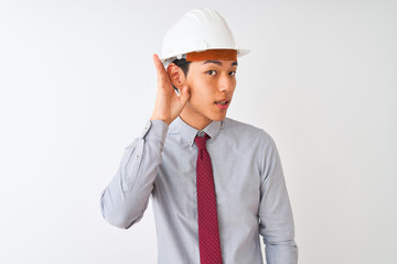 Wall Mural - Chinese architect man wearing tie and helmet standing over isolated white background smiling with hand over ear listening an hearing to rumor or gossip. Deafness concept.