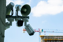 CCTV Cameras And Loudspeakers On A Wall Of A Building. There Is Building Under Construction In Background