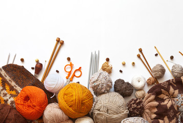 Tangles of orange, brown and beige wool yarn for hand knitting, accessories for knit, and knitted hats on a white background. The concept of crafts and hobbies. Copy space, flat lay, mock up