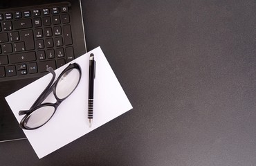 Office desk with laptop, paper, pen and glasses. Workplace concept.