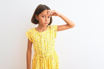 Canvas Print - Young beautiful child girl wearing yellow floral dress standing over isolated white background worried and stressed about a problem with hand on forehead, nervous and anxious for crisis