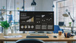 © Gorodenkoff - Shot of a Desktop Computer in the Creative Modern Office. Monitor Screen Shows Company Growth Data with Graphs, Charts, Software UI. In the Background Young Professional Looking for a Book.