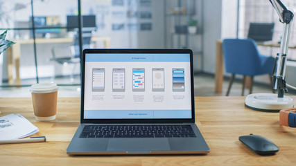 Wall Mural - laptop on the desk in the office shows screen with mobile phone application design, software ui deve