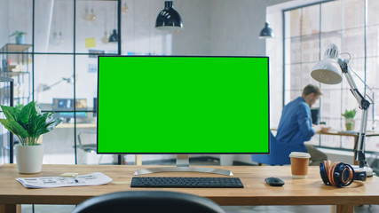 Wall Mural - wide green mock-up screen desktop computer standing on the desk in modern creative office. in backgr